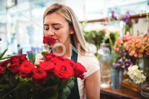Female Florist Smelling A Rose Flower In The Flower Shop
