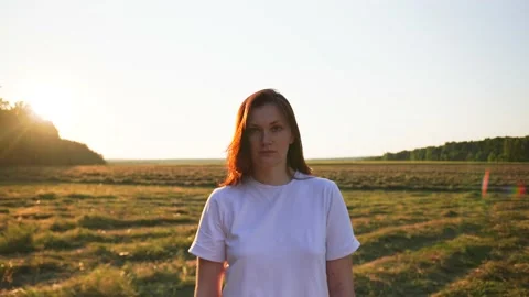 Female in the frame, the camera approaches, the field in the background, sunset Stock Footage 159121952
