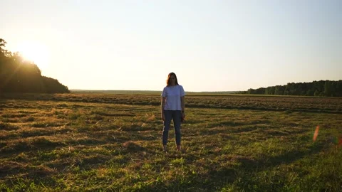 Female in the frame, the camera approaches, the field in the background, sunset Stock Footage 159121992