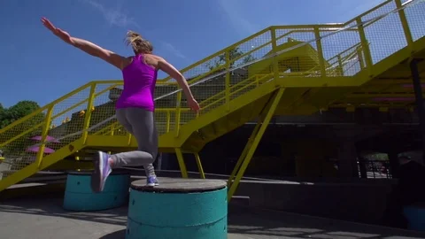 A female Free Runner or exponant of La parkour jumps onto a staircase. Vídeo Stock 80415718