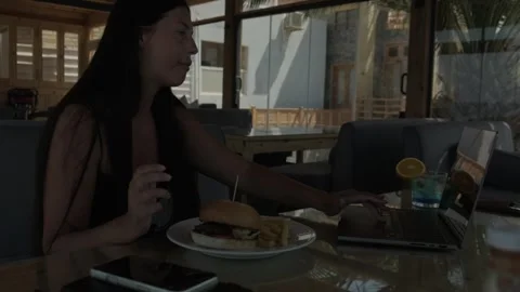 Female freelancer eating lunch while working on laptop in cafe remote worker Stock Footage 346251078