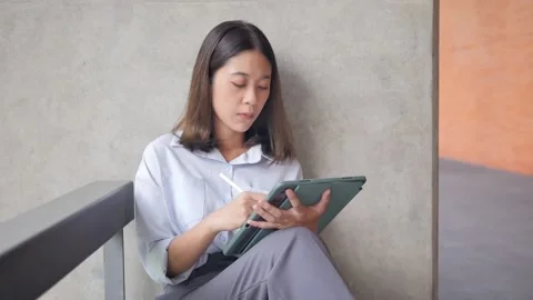 A female freelancer interacts with a tablet display using a stylus using a touch Stock Footage 201363160