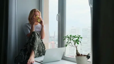 Female freelancer looking out the window while a break in work. Stock Footage 246156909