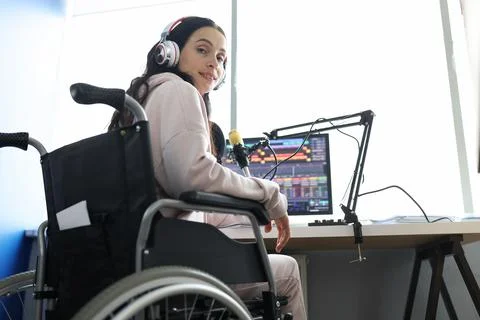 Female freelancer programmer or streamer in modern headphones sits in wheelchair Stock Photos