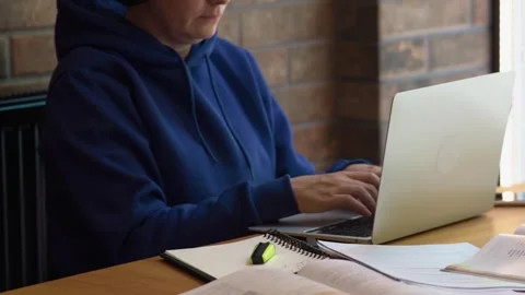 Female freelancer sitting brown table typing keyboard opened laptop, textbooks Stock Footage 243268606