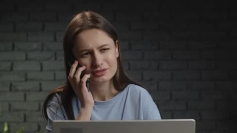 A female freelancer sitting in a studio calls her employer on the phone to Stock Footage 233283612
