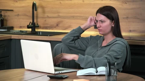 A female freelancer is surprised while working while sitting at the table in the Stock Footage 301654784