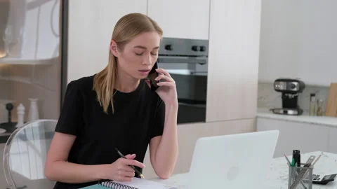 Female freelancer talking on the phone while working at home. Stock Footage 253409118