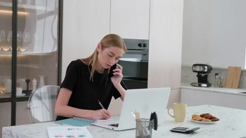 Female freelancer talking on the phone while working at home. Stock Footage 253410467