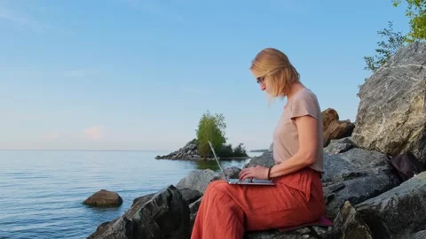 Female freelancer uses laptop computer on empty seashore. Видео 259154150