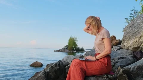 Female freelancer uses laptop computer on empty seashore. 動画素材 272846126