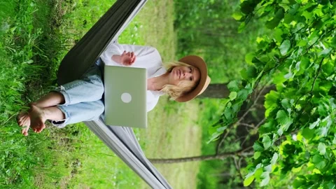 Female freelancer wearing hat using a laptop outdoors. Stock Footage 249782646