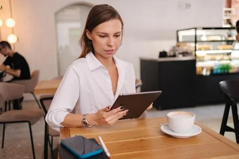 Female freelancer working in cafe using digital tablet. Young business manager Stock Photos