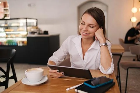 Female freelancer working in cafe using digital tablet. Young business manager Stock Photos