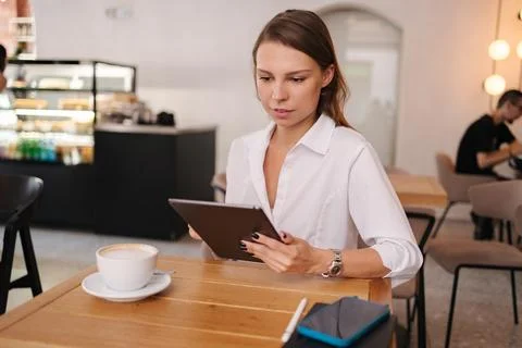 Female freelancer working in cafe using digital tablet. Young business manager Stock Photos