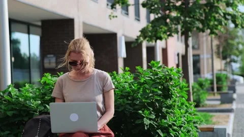 Female freelancer working online sitting on the bench outdoors. Stock Footage 246016572