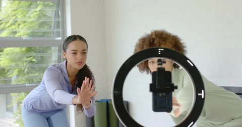 Female friends checking framing, adjusting phone-mounted ring light and aligning Stock Footage 341090430