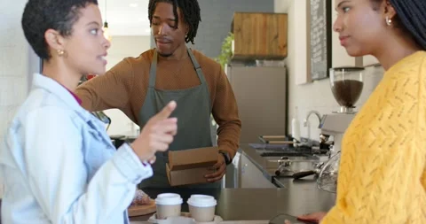 Female friends gesturing confirming order, barista packing coffee cups, pastry Stock Footage 342233210