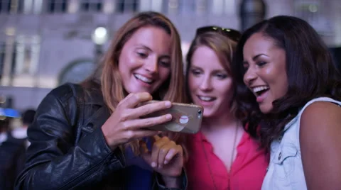 Female friends pull silly faces during a selfie in the city at night, in slow mo Stock Footage 67745425