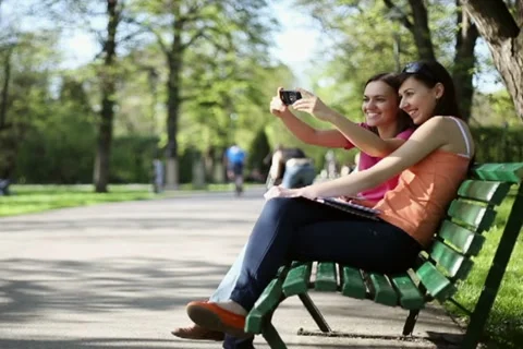Female friends taking picture of themselves from cellphone, tracking shot NTSC Stock Footage