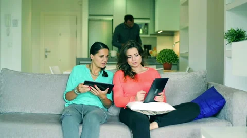 Female friends using tablets and man bringing them drinks Stockbeeldmateriaal 43245241