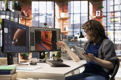 Female game developer interacts with AI powered assistant on computer 写真素材