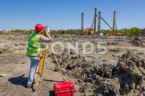 Female geodesist is working with total station on a building site. Stock Photos