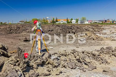 Female geodesist is working with total station on a building site. Stock Photos