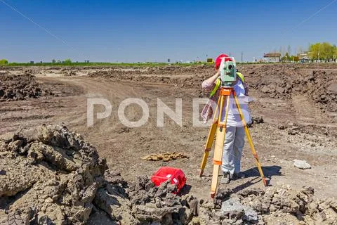 Female geodesist is working with total station on a building site. Stock Photos