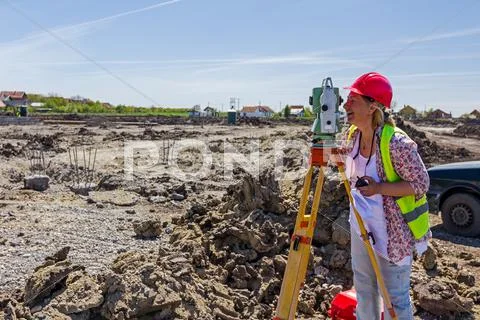 Female geodesist is working with total station on a building site. Stock Photos