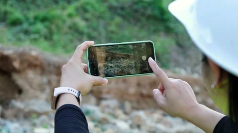 Female geologist using mobile phone to work on rock exploration Stock Footage 229712643