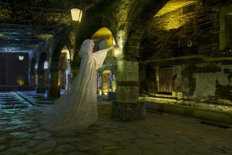 Female ghost with lantern, dressed all in white standing in a cavernous stone Stockfoto's