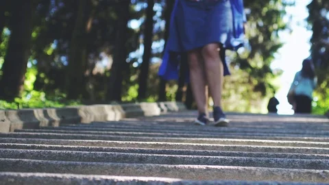 Female going down on stony stairs in a park in slow motion. Blurry background Stock Footage