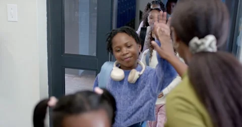 Female greeter right giving highfives as school girls peeking open glass door Stock Footage 341028154