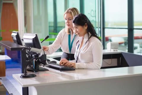 Female Ground Staff Using Computer At Counter In Airport Stock Photos
