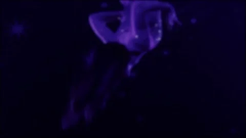 Female gymnast performing acrobatic routine illuminated by ultraviolet light, Stock Footage 344846998