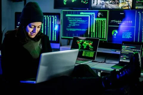 Female hacker breaking into corporate network using laptop and multiple screens Stock Photos