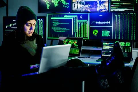 Female hacker breaking into corporate network using laptop and multiple screens Stock Photos