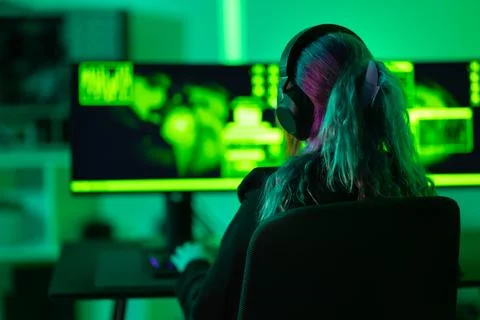 Female hacker working on cybersecurity tasks in a green lit room Stock Photos