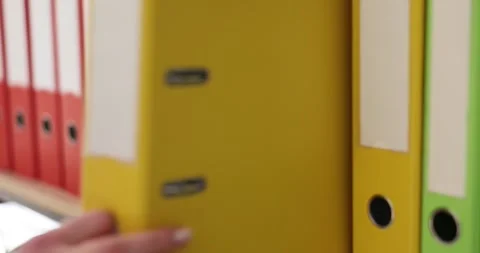 Female hand of accountant pulls binder folder from storage shelf Stock Footage 241680656