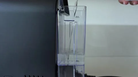 Female hand adding fresh filtered water into small black coffee machine Stock Footage 139515479