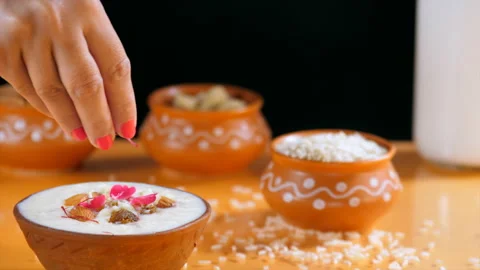 Female hand adding saffron / Kesar to a bowl of delicious rice pudding at home Stock Footage 158196035