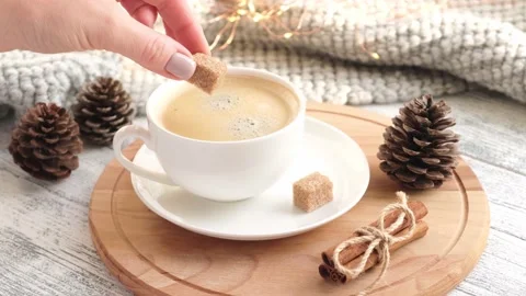 Female hand adding white sugar cube in cup of coffee on table. Close-up, slow Stock Footage 165336786