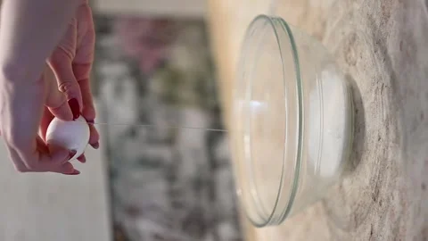 Female hand break an egg into a transparent glass bowl Stock Footage 275539155
