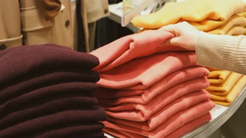 Female hand chooses folded clothes on shelf in a store close-up. Stock Footage 169398933