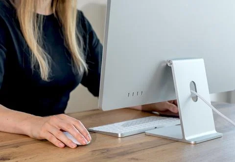 Female hand clicking on computer mouse while working from home office. Remote Stock Photos