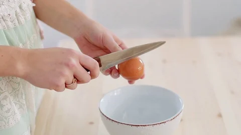 Female hand cracks a fresh egg by knife. Stock Footage 70942756