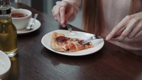 A female hand cuts and eats a slice of pizza, close-up shot. In a cafe Stock Footage 74807620