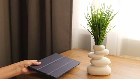 A female hand delicately sets down a sleek tablet on the table. Discover the Stock Footage 273676744