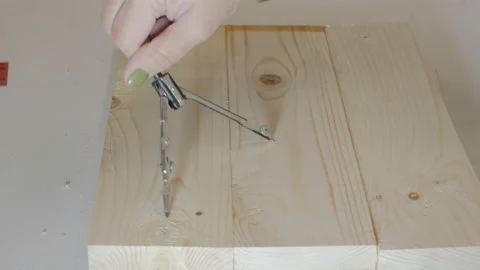 A female hand draws a circle with a compass on a wooden product in order to cut Video stock 142958721